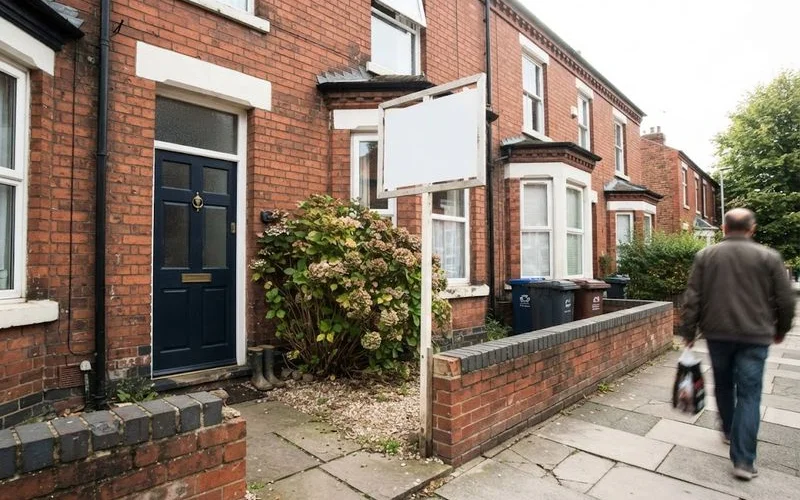A "For Sale" board outside a terraced house in a Birmingham residential street